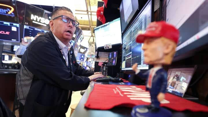A trader is concerned about the stock market while Trump swag looks on. 