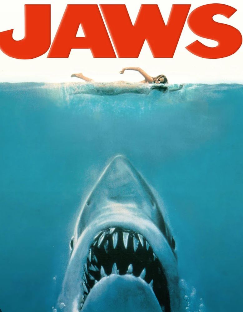 The old school jaws movie poster with the great white shark coming up, and the chin and nose of the shark is in exactly the same position as the cat chin and mouth from the other picture