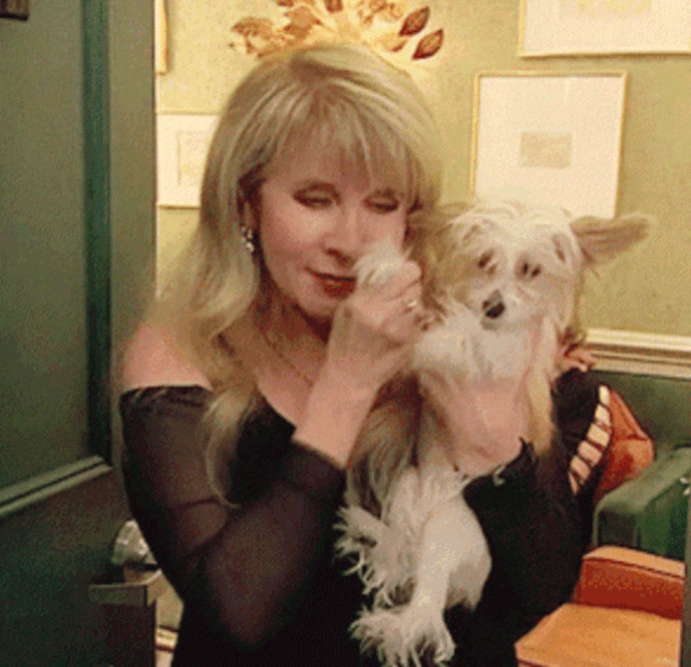 a woman holds a small dog in her arms