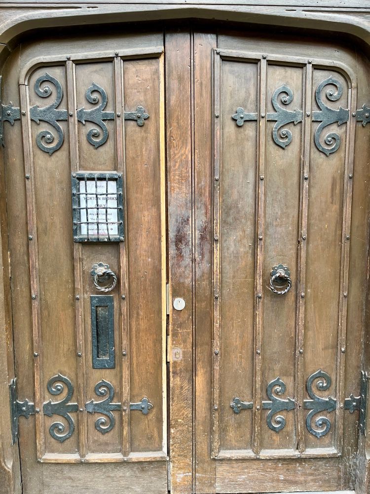 Double wooden door in wooden doorway with glass window and iron hinges 
