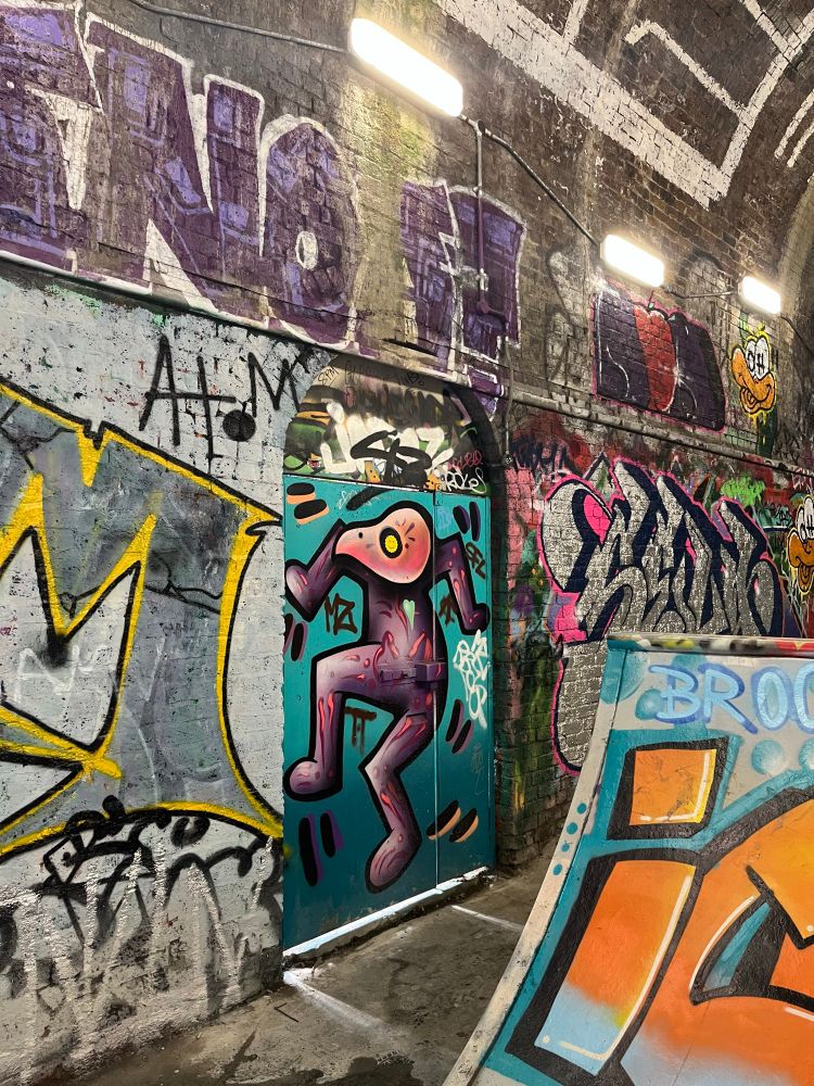 Railway arches turned skatepark brick walls with graffiti on ramps