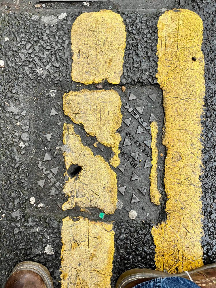 Tarmac Road with road markings on manhole and drain covers.