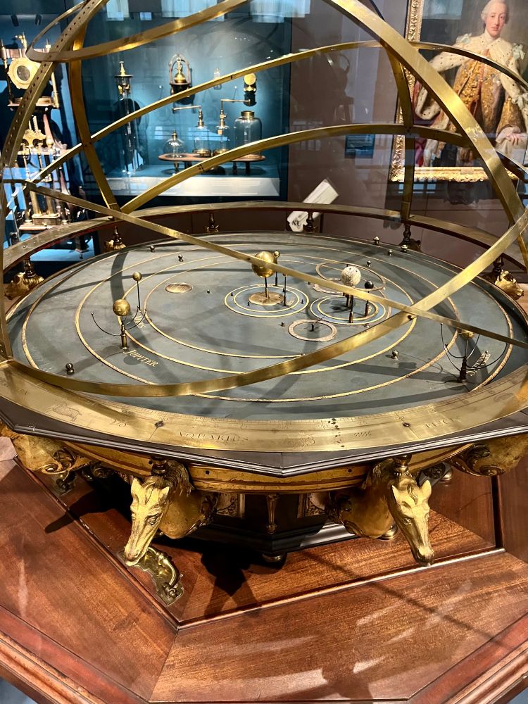 This ornate orrery was owned by Queen Caroline, wite of King George It was originally installed in her gallery at Kensing malace Caroline took a keen interest in science ano and discussed ideas and experiments with philosooners including Isaac Newton. Both she and King George Ill's wife, Queen Charlotte, possessed fine collections of scientific books and instruments, which they shared with their children.
Modified and enlarged by Thomas Wright, Fleet Street, London Lent by King's College London. Object no. 1927-1659

Text from display 