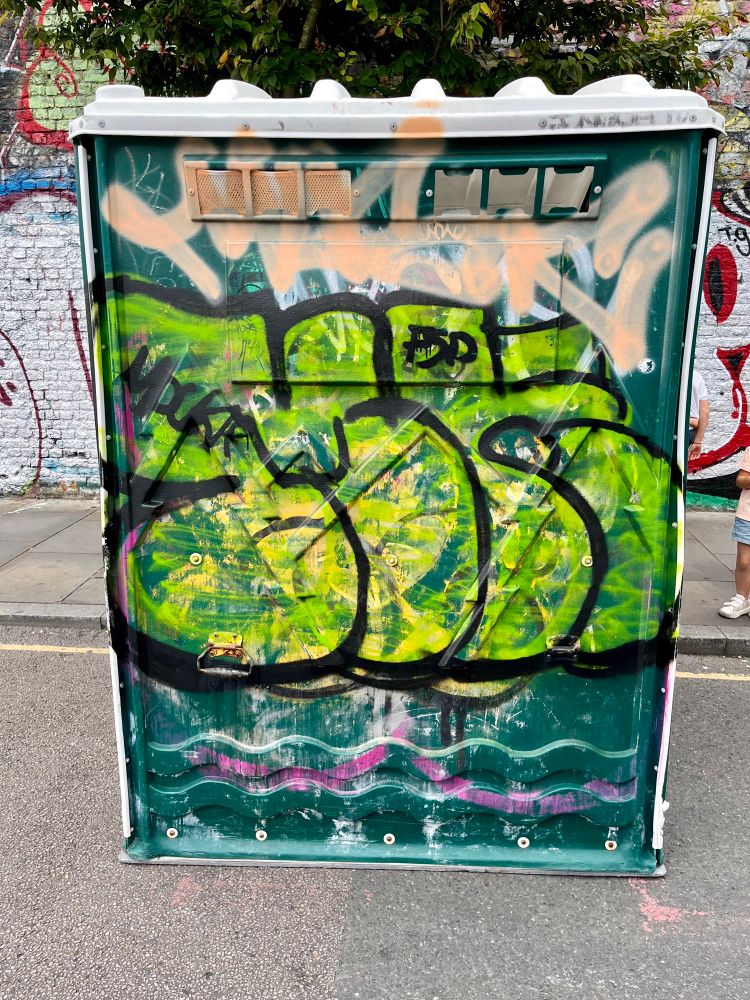 Public open sided porta potty urinal with graffiti    