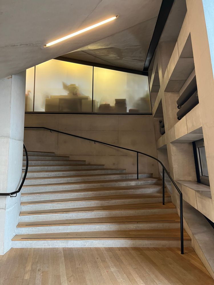 Concrete staircase with recessed lighting with fogged glass office window  