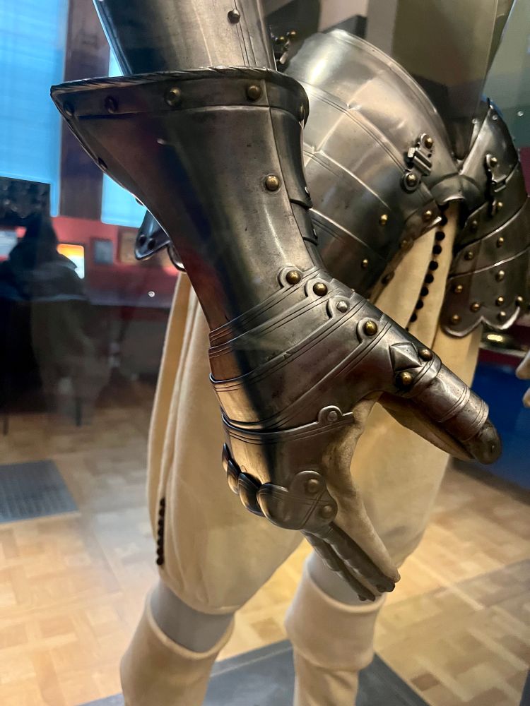 This half-armour was made for the tilt - a popular pastime for noblemen in about 1600, involving combat on horseback. Only the upper part of the body required protection. The breastplate had an attachment for a lance-rest and a reinforcing plate (grandguard) for the left shoulder. Underneath the armour a soft arming-doublet protected the skin from the hard metal and also provided some warmth. The illustration shows Charles, Prince of Wales (later Charles I) wearing a similar half armour.

Text from display 