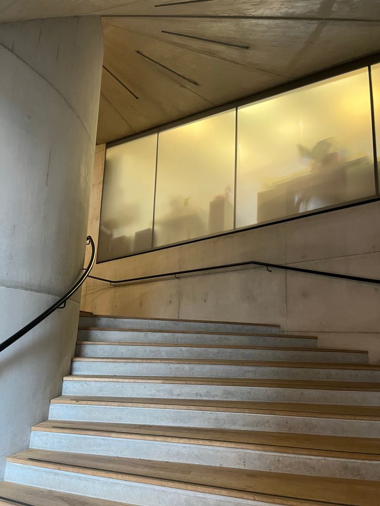 Concrete staircase with recessed lighting with fogged glass office window  