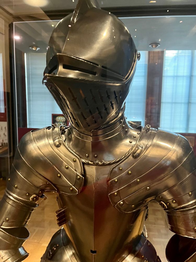 This half-armour was made for the tilt - a popular pastime for noblemen in about 1600, involving combat on horseback. Only the upper part of the body required protection. The breastplate had an attachment for a lance-rest and a reinforcing plate (grandguard) for the left shoulder. Underneath the armour a soft arming-doublet protected the skin from the hard metal and also provided some warmth. The illustration shows Charles, Prince of Wales (later Charles I) wearing a similar half armour.

Text from display 
