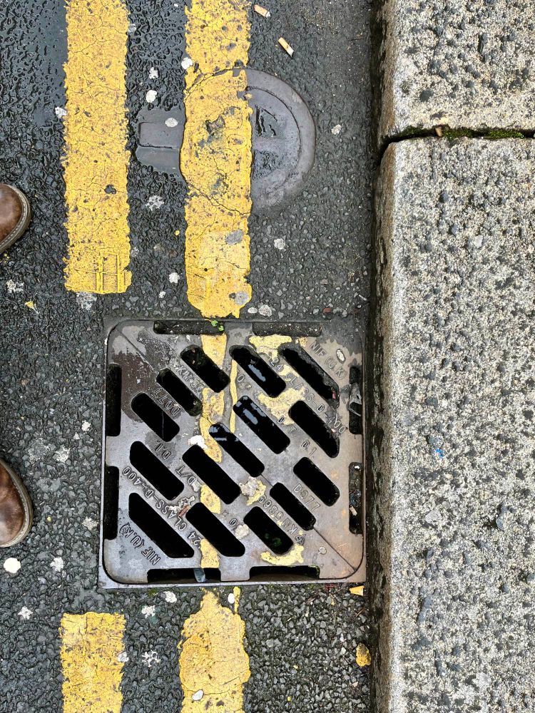 Tarmac Road with road markings on manhole and drain covers.