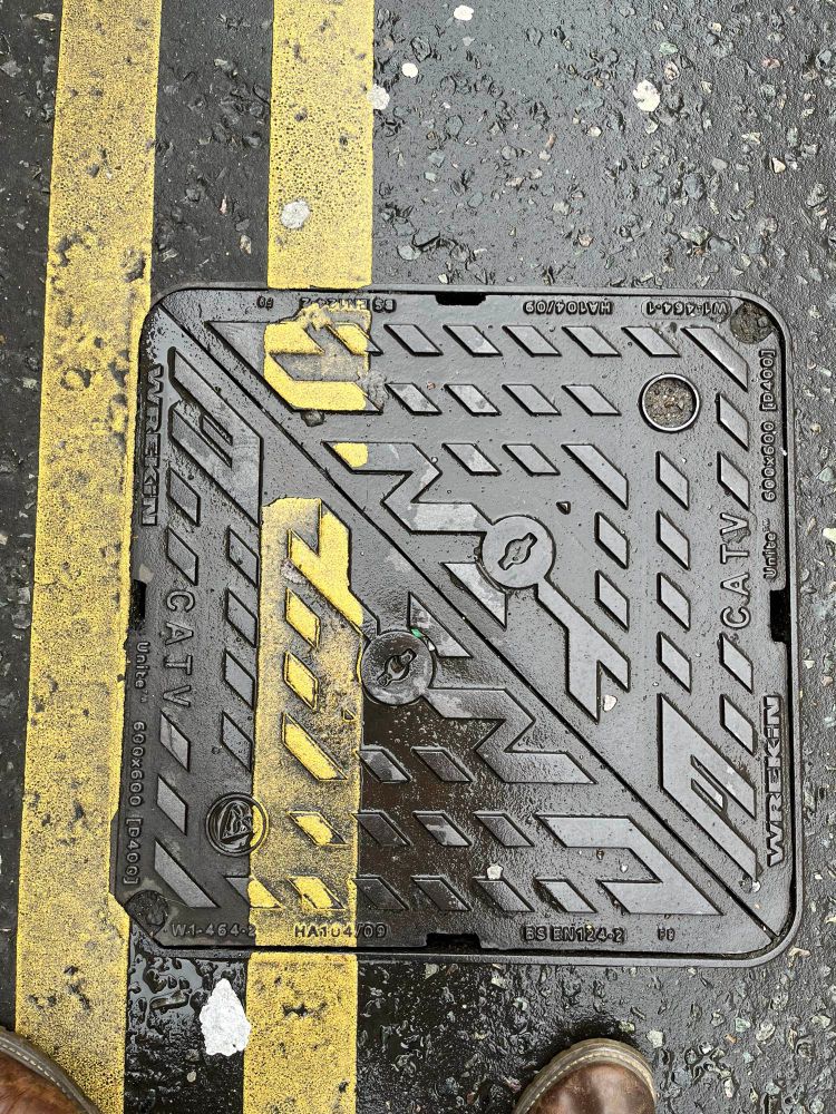 Tarmac Road with road markings on manhole and drain covers.
