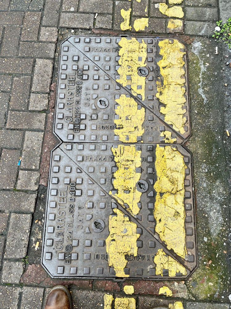 Tarmac Road with road markings on manhole and drain covers.