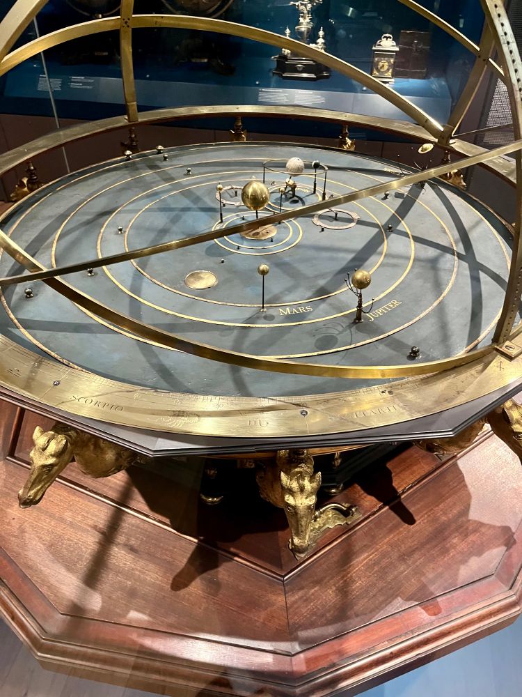 This ornate orrery was owned by Queen Caroline, wite of King George It was originally installed in her gallery at Kensing malace Caroline took a keen interest in science ano and discussed ideas and experiments with philosooners including Isaac Newton. Both she and King George Ill's wife, Queen Charlotte, possessed fine collections of scientific books and instruments, which they shared with their children.
Modified and enlarged by Thomas Wright, Fleet Street, London Lent by King's College London. Object no. 1927-1659

Text from display 
