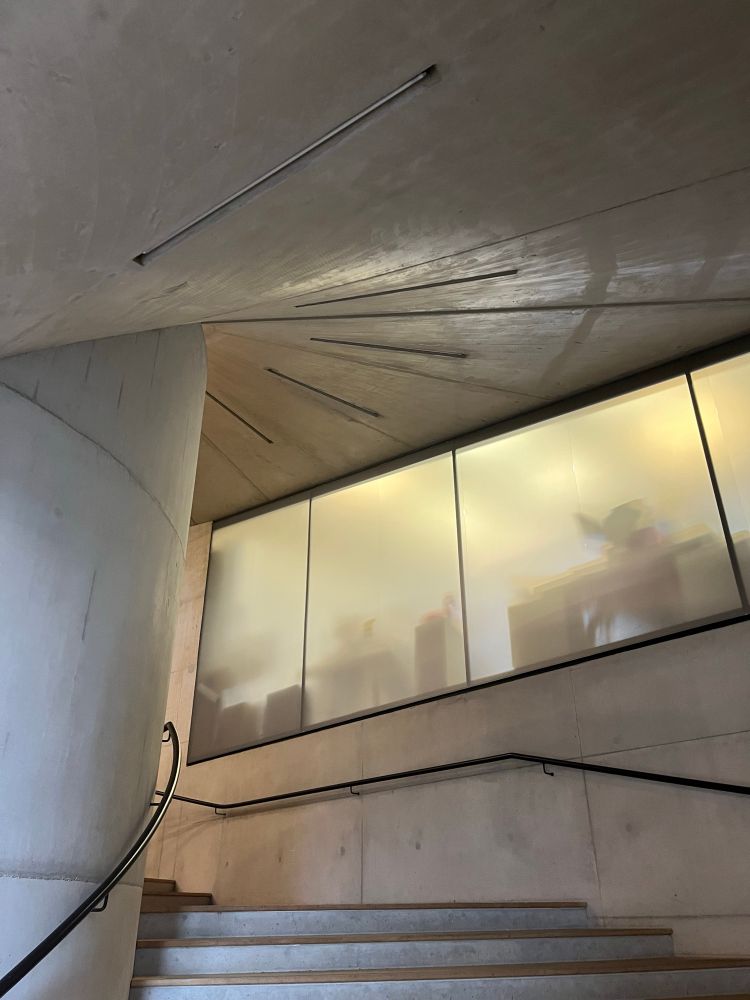Concrete staircase with recessed lighting with fogged glass office window  