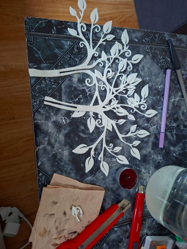 die zwei weißen 3d gedruckten zwei dimensionalen bäumchen, 2 teppichmesser und eine kerze daneben.