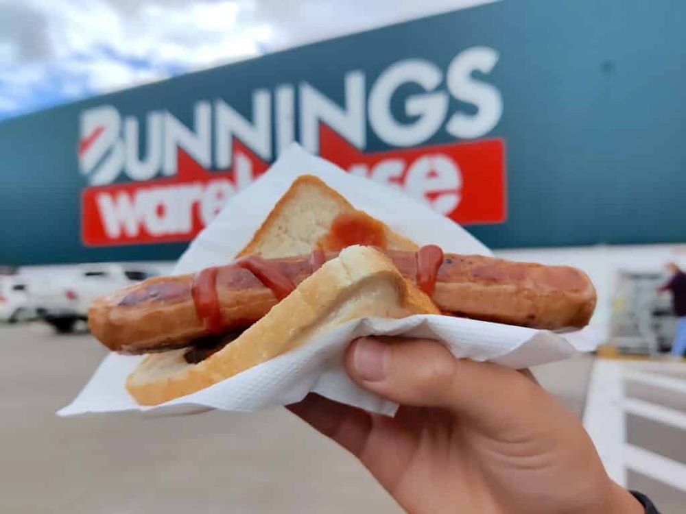 a sausage sizzle (grilled sausage on a piece of white bread with tomato sauce) from bunnings (hardware store)