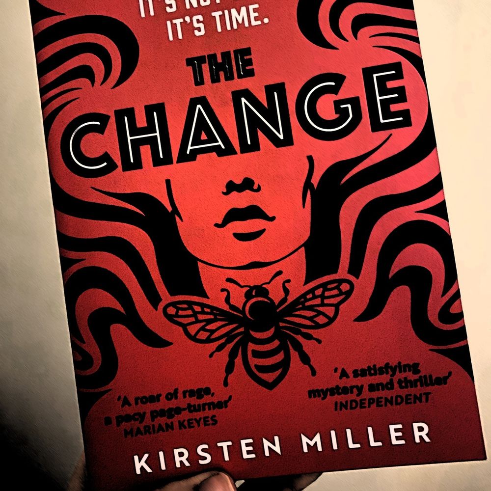 Photo of the front cover of 'The Change' by Kirsten Miller. The book is being held up against a light-coloured background