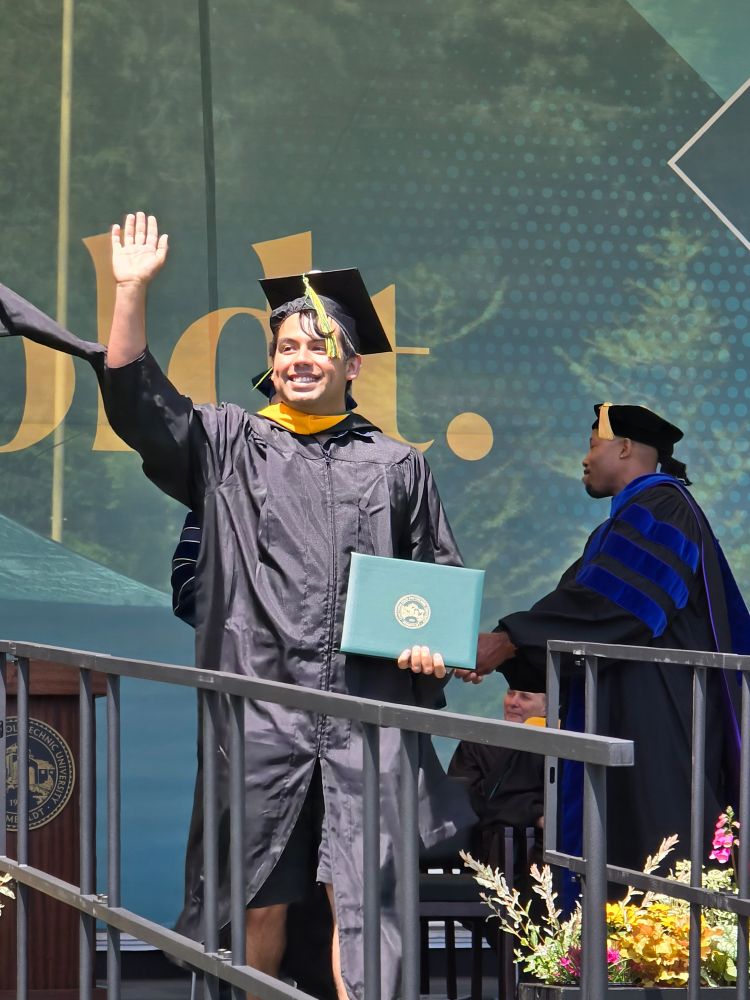 Ernesto Chavez-Velasco, M.S., walking across the stage with their diploma 