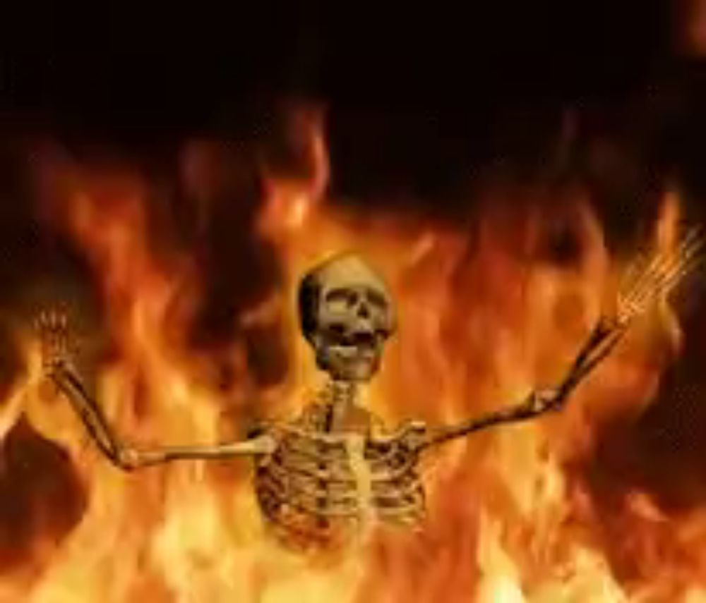 a skeleton is standing in the middle of a fire with his arms outstretched .