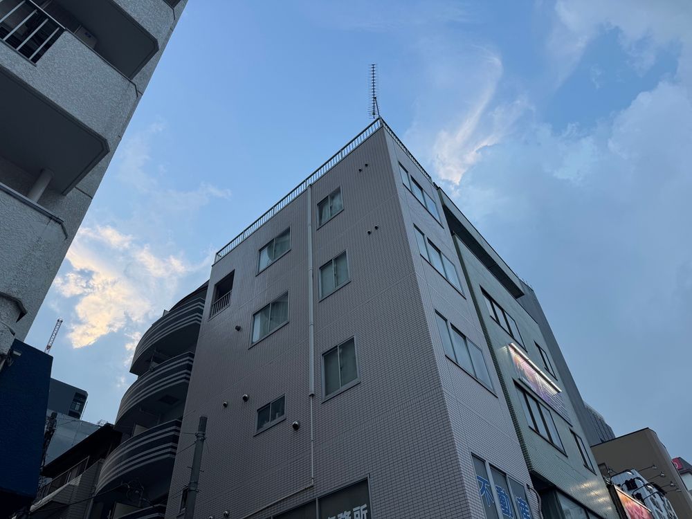 Worm’s eye view of compact tower with one suite per floor, clad in light pink ceramic tile. 