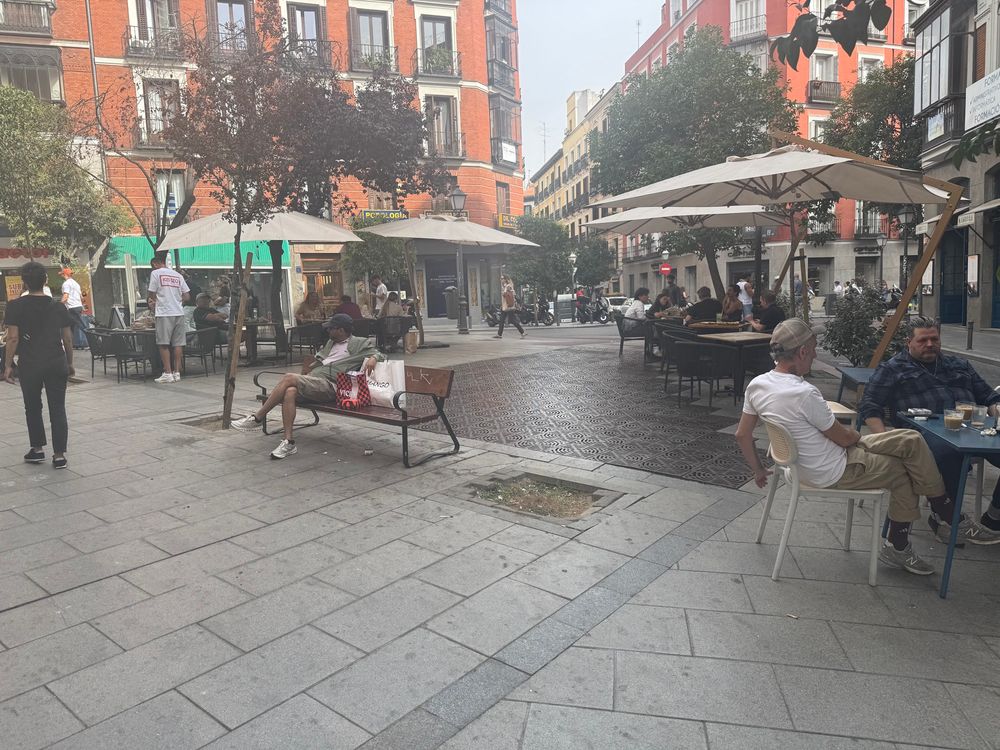 Public plaza in Madrid featuring cafe and restaurant seating alongside public benches 
