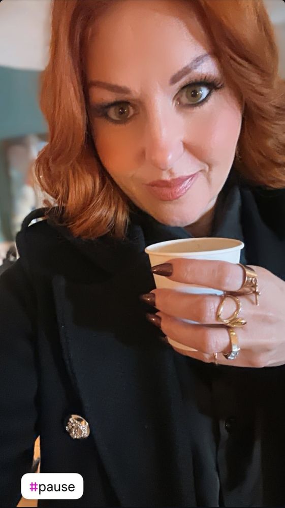 Cindy Sander tenant un café dans la main, en bas à gauche on voit noté le hashtag pause