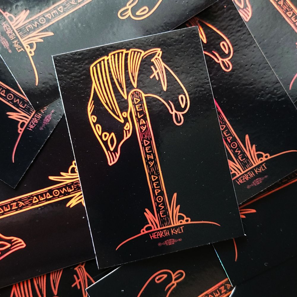 photo of a pile of stickers featuring a niðstang, with the curse "DELAY, DENY, DEPOSE" carved into the pole.