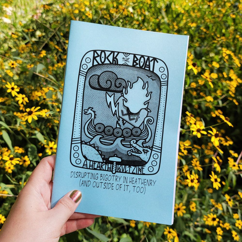 photo of my hand holding up a zine in front of a meadow of black eyed susans. the zine has a blue cover, and the title is 