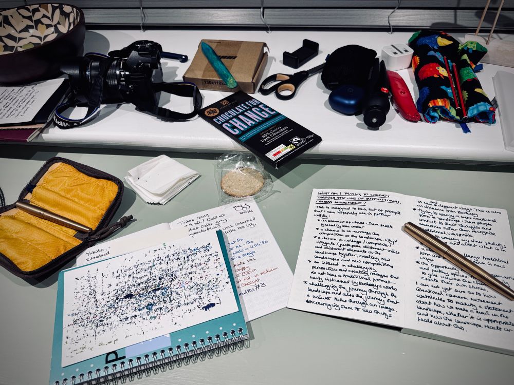 An image of the desk and shelf at a small holiday cottage in Cornwall. It is filled with notebooks, pens, my camera and various artistic and bookmaking tools. If you look carefully, you can read a little bit about what I'm trying to achieve with my use of intentional camera movement.
