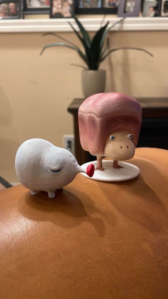 A small hand painted figurine of a blowhog from pikmin, next to a hand painted 3d printed figure of a breadbug from pikmin2