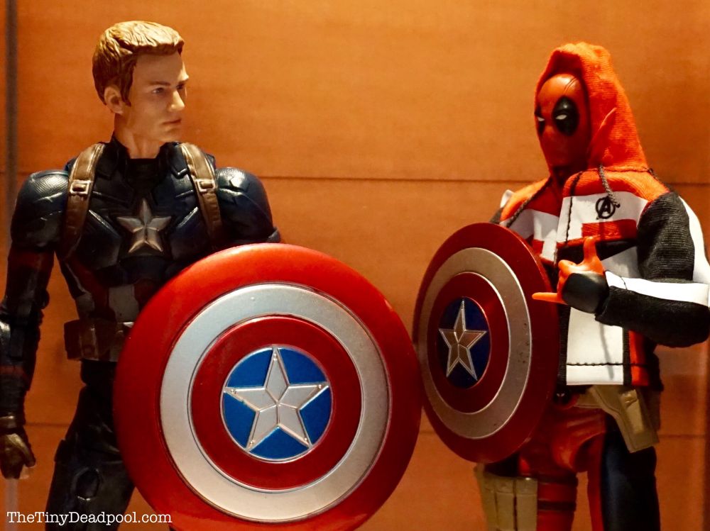 Deadpool gives captain America his elevator pitch on joining the avengers while also holding a shield and wearing an avengers hoodie 