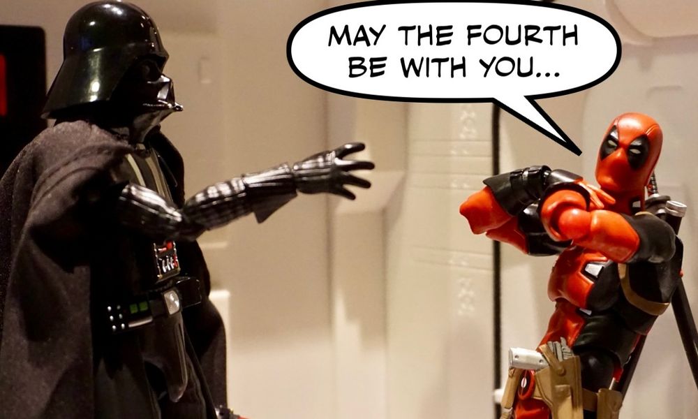 Darth Vader force chokes Deadpool in a hallway while Deadpool grabs his throat look toward the camera and says “may the 4th be with you”