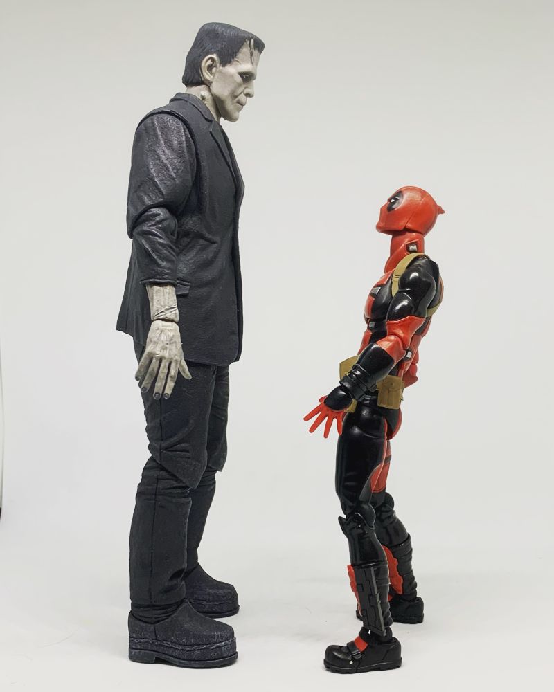 Deadpool leans back to look up at Frankenstein’s monster 