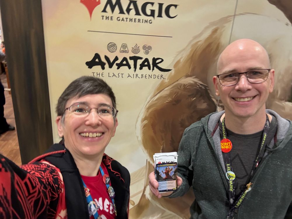 Selfie with hubby in front of the Magic the Gathering Avatar the Last Airbender booth holding four jumpstart boosters 