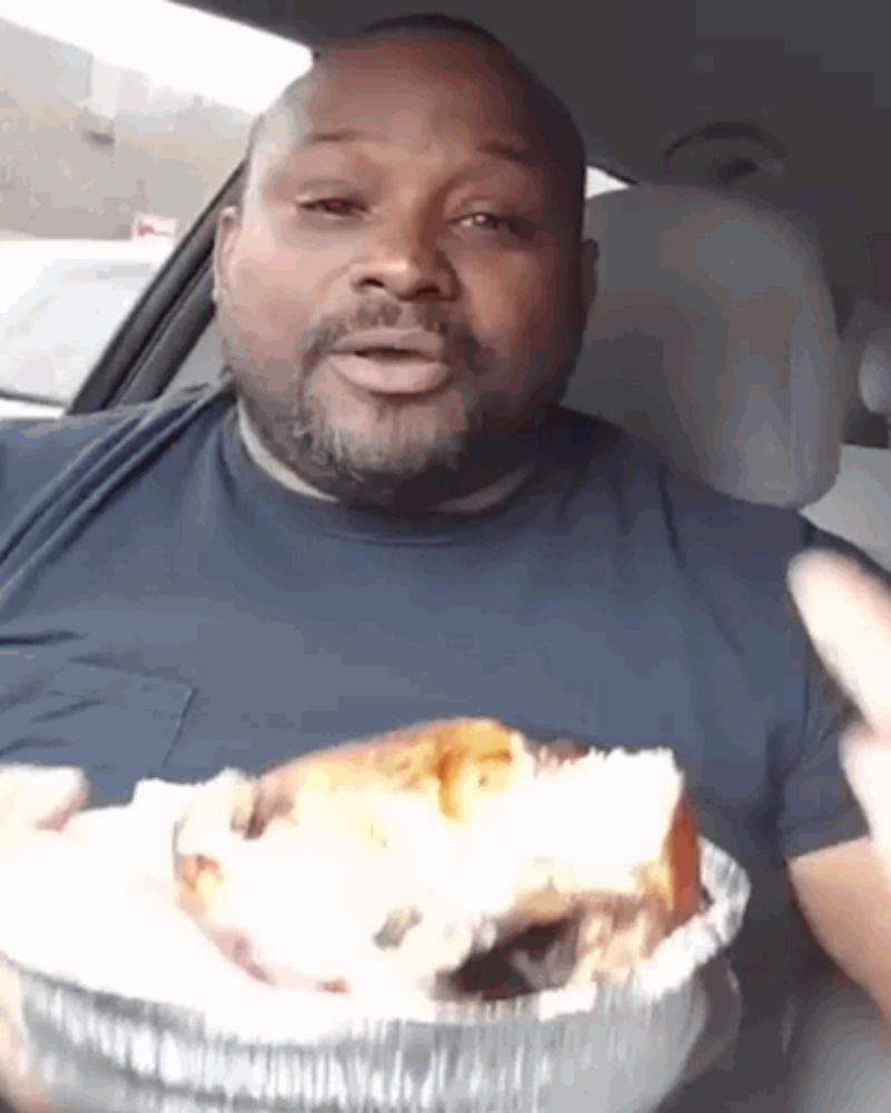 a man in a car is eating a sandwich