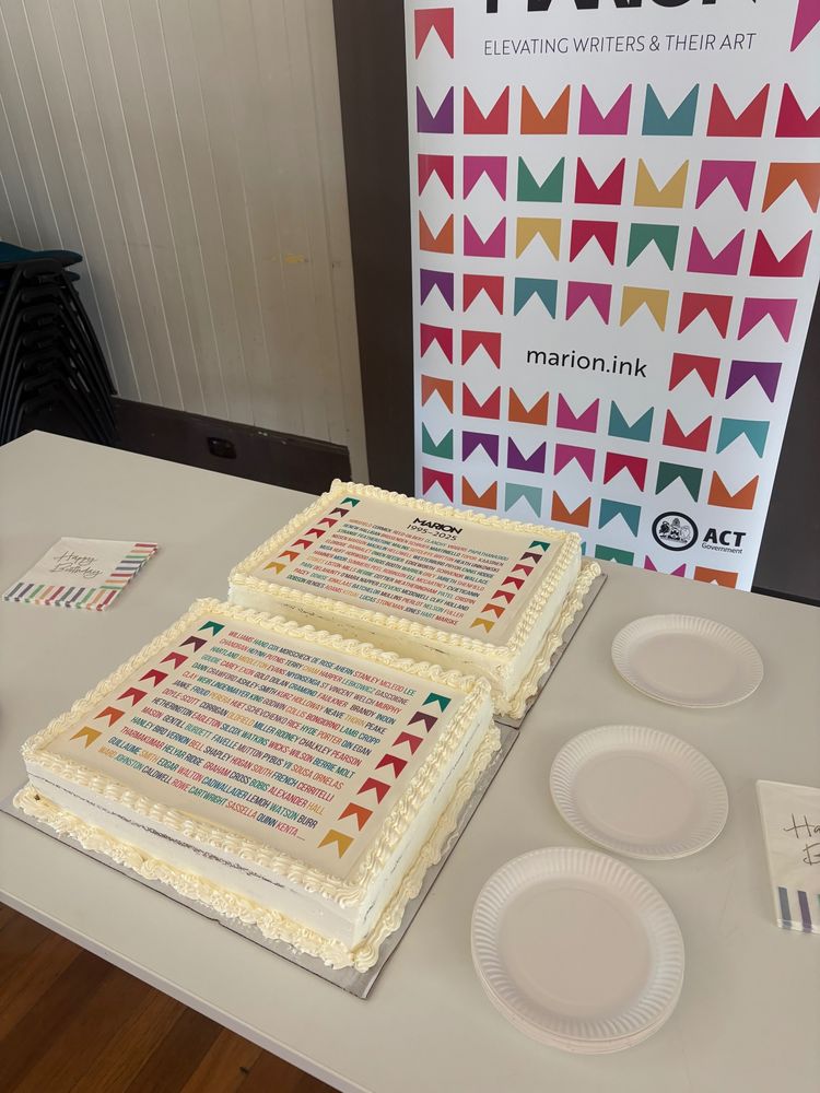 A photo of two cakes with surnames on them. There is a banner behind the cakes with the MARION motif on it, and the ACT Government logo. Paper plates and serviettes surround the cakes.