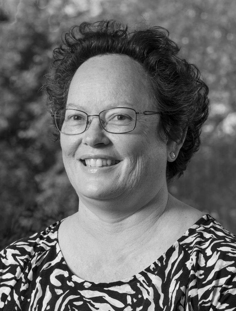 A black and white photo of Samantha Faulkner smiling and looking at the camera.