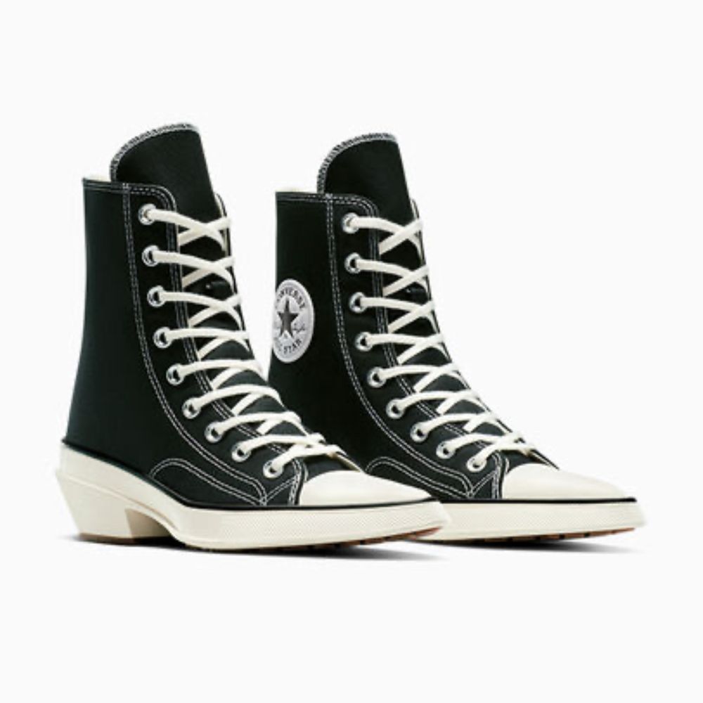 A black and white converse shoe but it’s a pointy heeled boot 