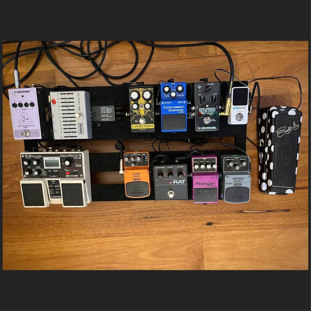 Guitar effects pedals velcroed to a PedalTrain pedalboard. The pedals are, in retrospect, a surprisingly monochrome bunch, with only the two Boss pedals (blue and magenta) and the Behringer pedal (orange) - itself a Boss clone, really standing out. At least the wah pedal has polka-dots.