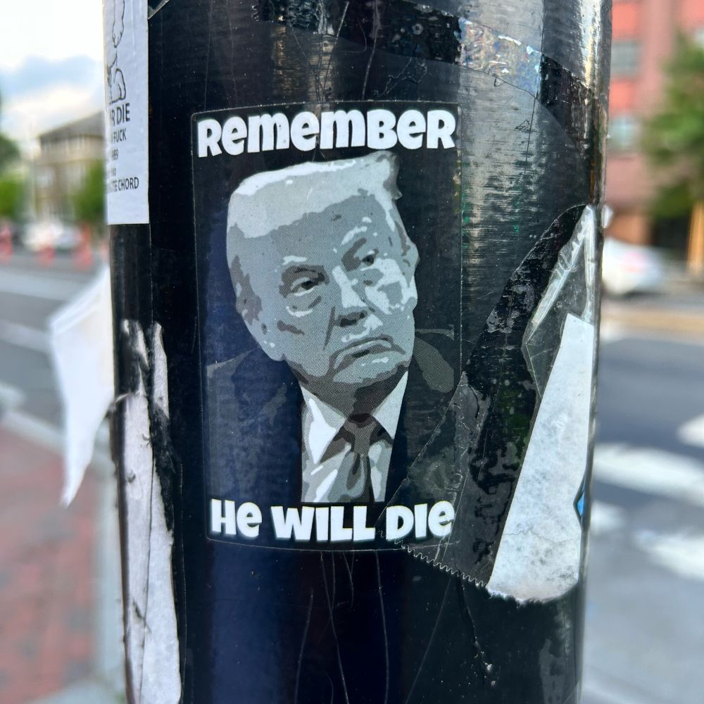 Sticker on a pole: Trump framed by the words REMEMBER - HE WILL DIE