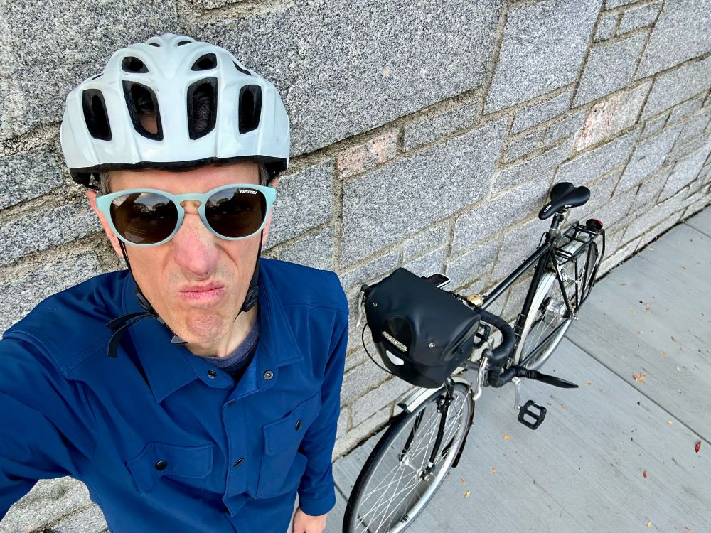 posing with my black fendered bike, wearing a bike helmet and scowling most unattractively