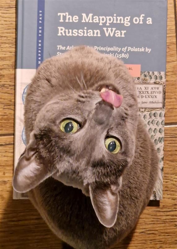 Grey-haired cut sitting on a book copy of "The Mapping of a Russian War"