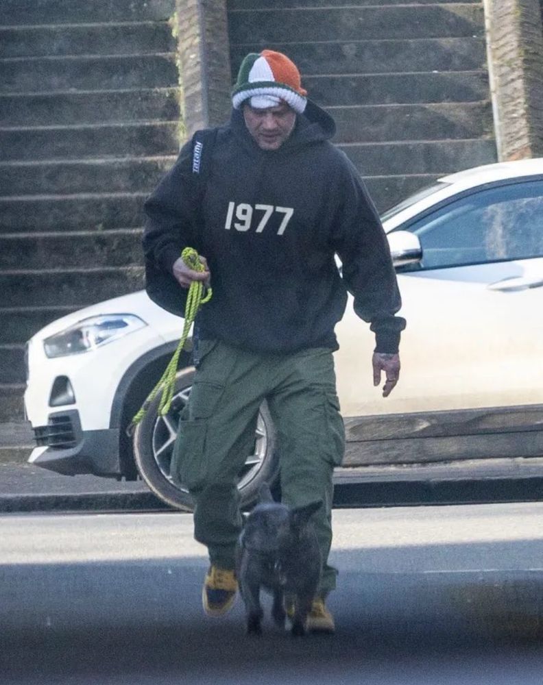 Tony Hardy’s face visible after pulling up his Irish tricolour balaclava while walking his extremely cute dog 🐶 