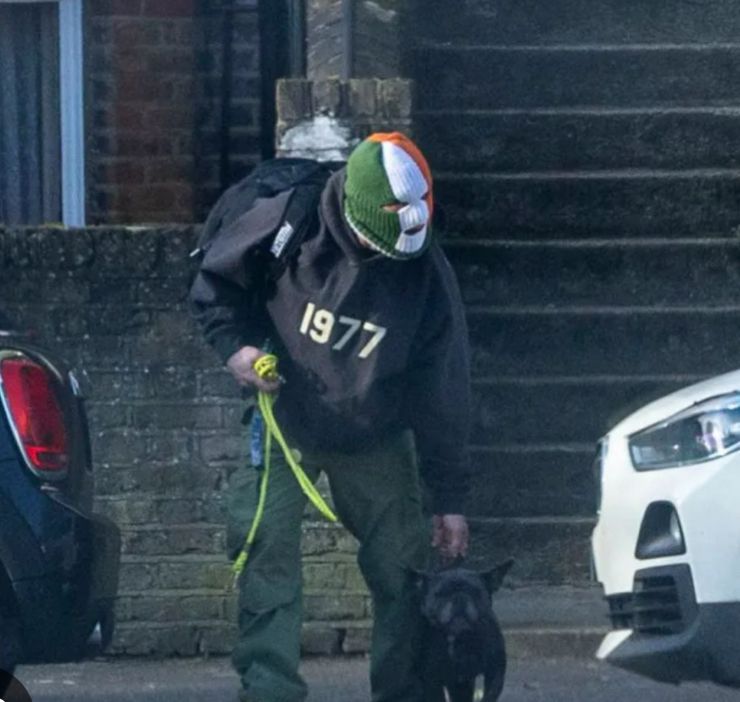 Tony Hardy wearing an Irish tricolour balaclava while walking his cute dog.