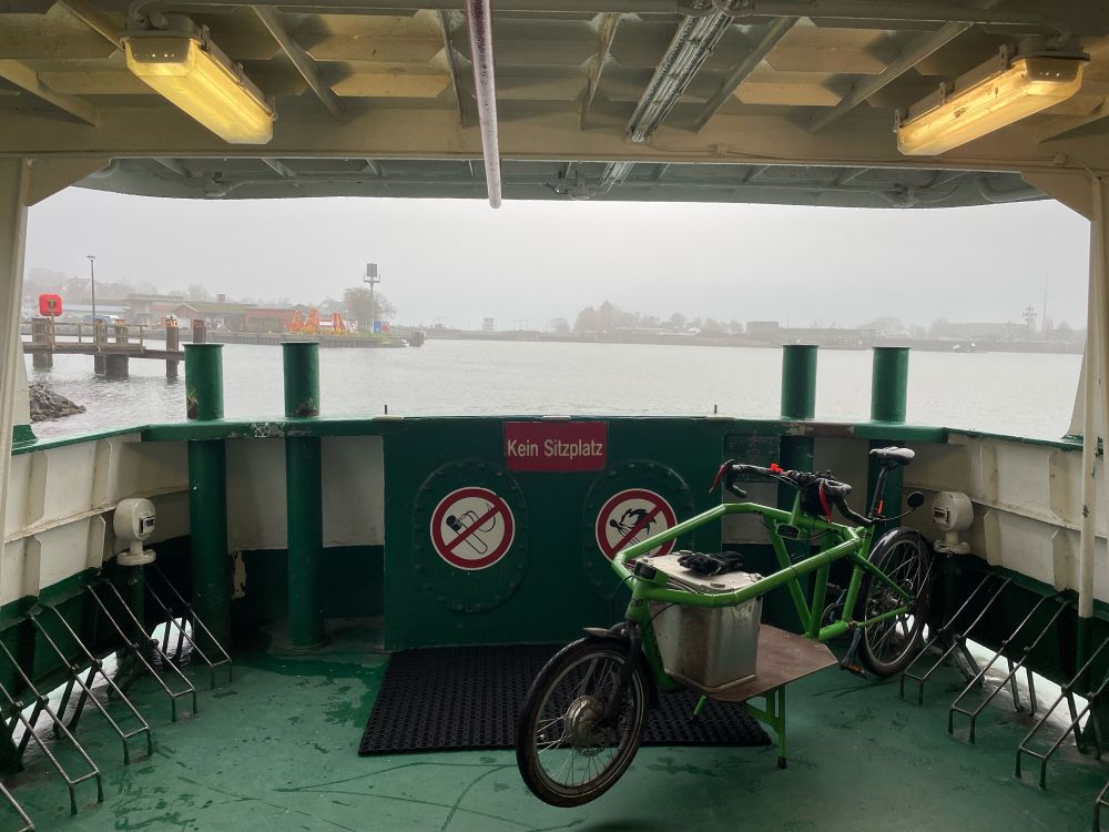 Von der N-O-Kanalfähre „Adler I“ aus dem offenen Heck heraus Block auf die vernebelten Holtenauer Schleusen. Im Vordergrund ein Radlader Lastenfahrrad.