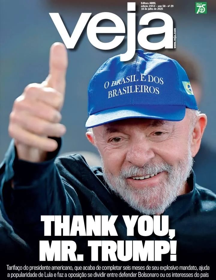 Lula surge com boné azul com os dizeres “O BRASIL É DOS BRASILEIROS” bordados em branco. Ele sorri e faz sinal de joinha com a mão direita, olhando para a câmera com semblante tranquilo e confiante. A foto tem fundo desfocado em tom azul, remetendo a um ambiente ao ar livre ou de comício. No topo, o título “Veja” permanece. A manchete da capa, em letras garrafais, diz “THANK YOU, MR. TRUMP!” (Obrigado, Sr. Trump!), numa ironia direta. A linha fina explica que a tarifa imposta pelo presidente americano — que teria completado seis meses de mandato — acabou fortalecendo a popularidade de Lula no Brasil e criando divisão na oposição entre defender Jair Bolsonaro ou os interesses econômicos nacionais.