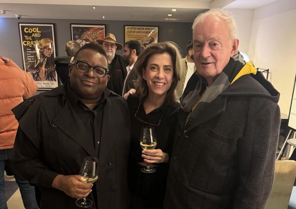 Isaac Julien, Fernanda Torres e Mark Nash posam para uma foto juntos em um ambiente interno, após a exibição de "Ainda Estou Aqui", em Londres. Isaac Julien, à esquerda, veste uma roupa preta e segura uma taça de vinho branco, sorrindo para a câmera. Fernanda Torres, ao centro, usa uma blusa preta, segura outra taça de vinho branco e também sorri. Mark Nash, à direita, está com um casaco escuro e um cachecol, sorrindo suavemente. Ao fundo, há pessoas conversando e pôsteres de filmes, incluindo um com o título "Cool and the Crazy".

Créditos: Fonte IG do Isaac.