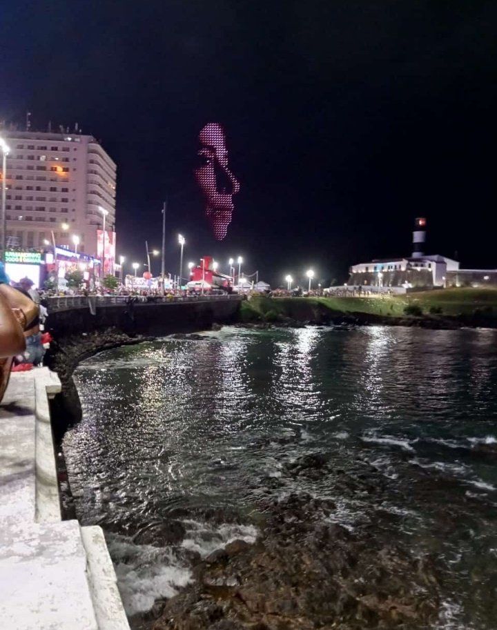 Rosto gigante de Fernanda Torres sendo projetado ao lado do Farol da Barra