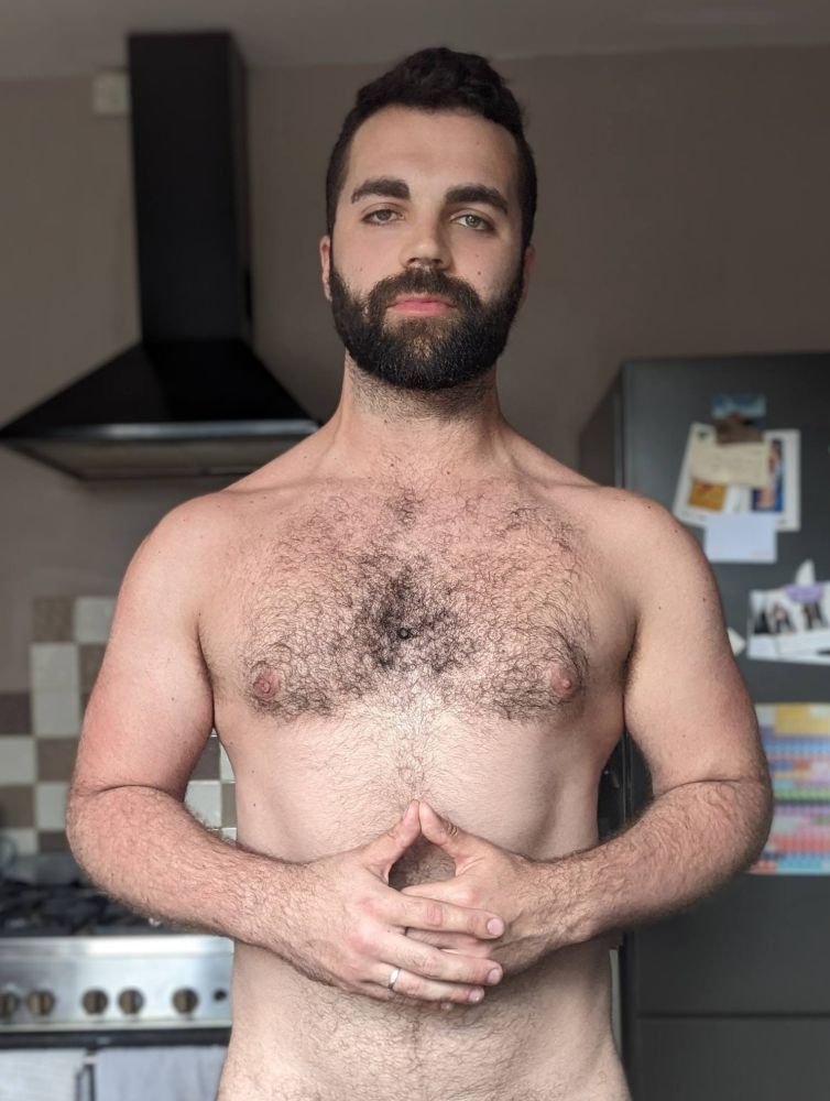 A selfie of me standing in the kitchen, topless, taken in August 2024.