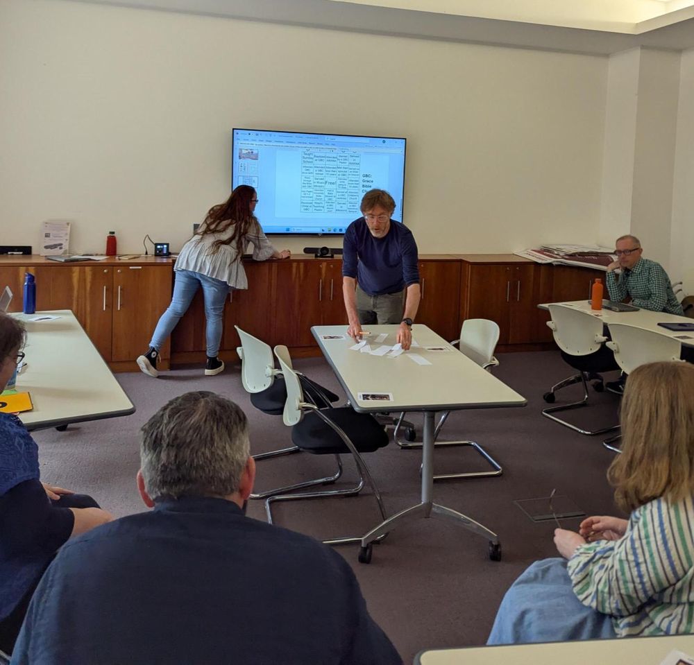 A presenter places slips of paper on a table for a getting creative with words activity. 