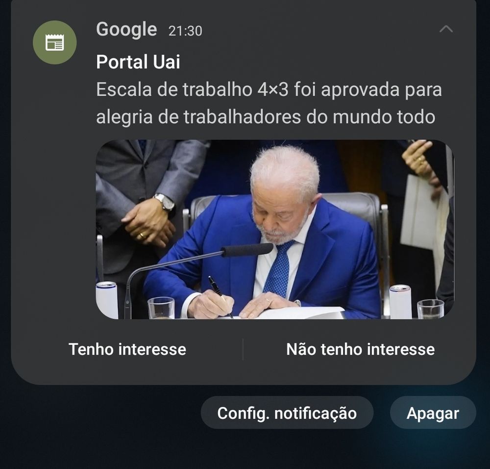 Na imagem um print de uma notícia nas notificações do celular que diz "Escala de trabalho 4x3 foi aprovada para alegria de trabalhadores do mundo todo". Logo abaixo uma foto de Lula com terno azul assinando um documento.